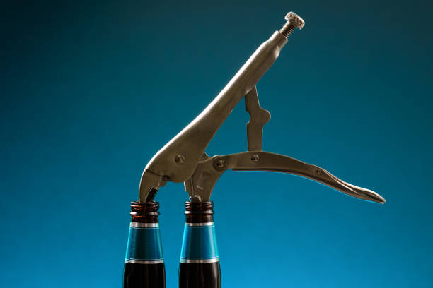 Pliers inserted into two empty bottles on fancy background. Empty beer bottles joined together with a clamp. Allegory of beer bottles and pliers as art concept for posters and banners. stock photo