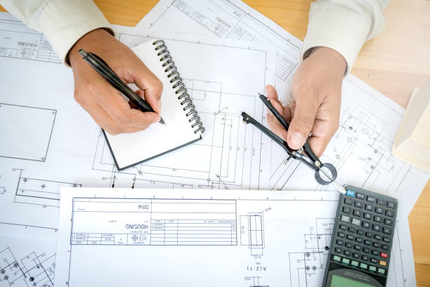istock Close up of civil male engineer asian working on blueprint architectural project at construction site at desk in office. 938712708