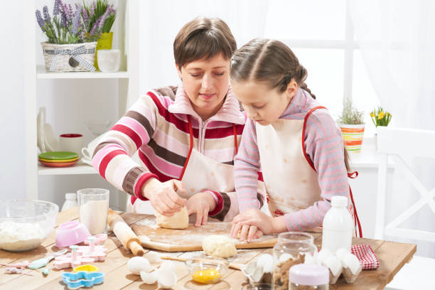 istock Mother and daughter cooking at home, making the dough for buns 938713040