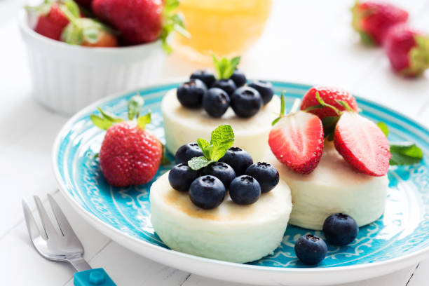 mini cheesecake o syrniki o frittelle di ricotta con bacche fresche su piatto blu - dessert fruit torte red foto e immagini stock