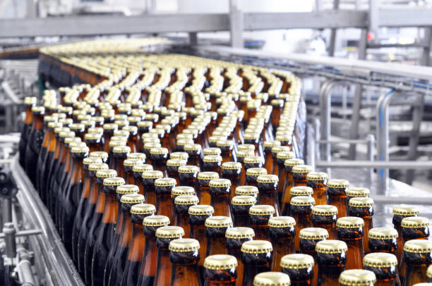 beer filling in a brewery - conveyor belt with glass bottles beer filling in a brewery - conveyor belt with glass bottles bottling plant stock pictures, royalty-free photos & images