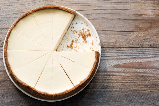 New York Cheesecake or Classic Cheesecake sliced on rustic wood, top view with copy space for text