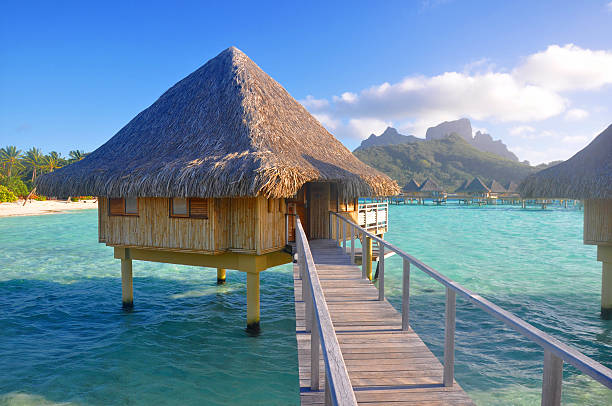 A bridge spanning over blue water to an overwater bungalow  A photo taken of a luxury overwater bungalow on the island of Bora Bora, Tahiti. bungalow stock pictures, royalty-free photos & images