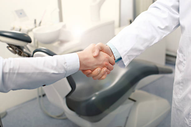 A dentist and a patient are handshaking stock photo