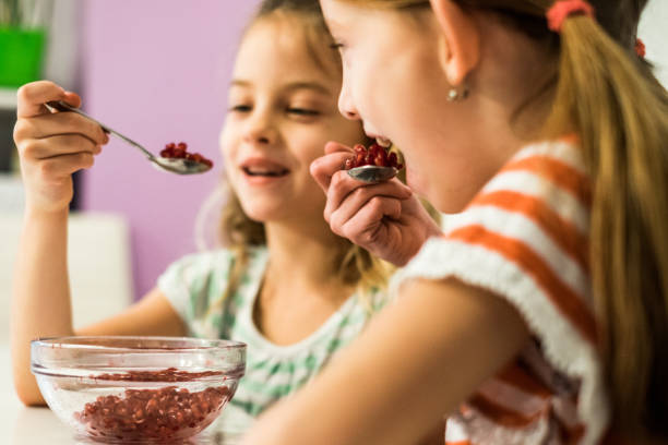 istock Happy faces two cute girls eating pomegranate 938733592