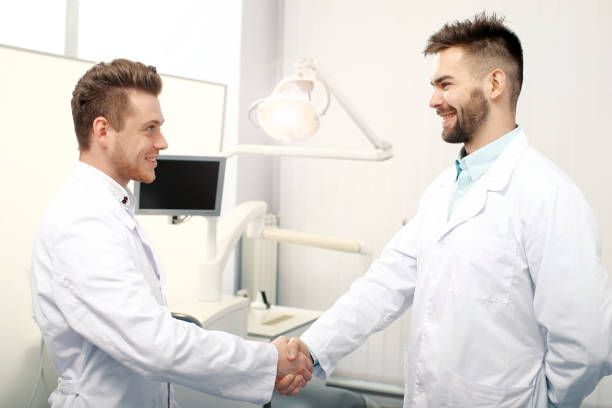 istock Two male doctors handshaking in the dentist office 938733602