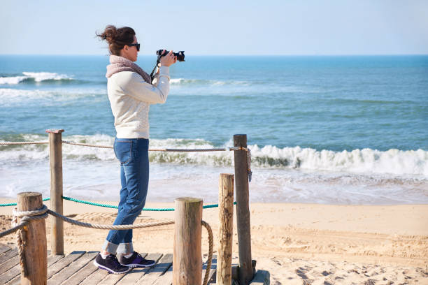 istock Woman photographer taking photos at a beach 938736464