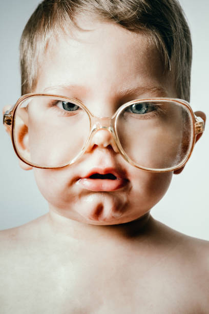 A cute baby wears large rimmed glasses frames.  Close up portrait.  Depiction of intelligence and learning in young children.