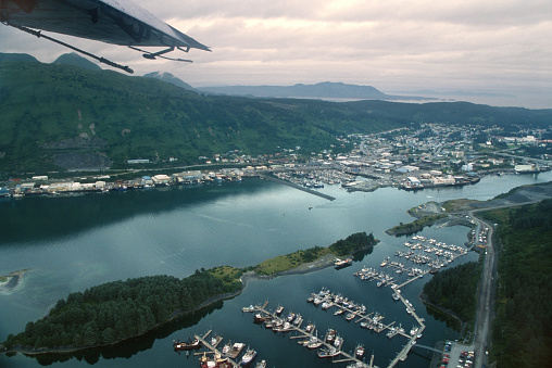 Fishing boats motor in the Pacific Ocean and fill the docks and port of Near Island and the town of Kodiak on the mountainous island of Kodiak Island in Alaska.