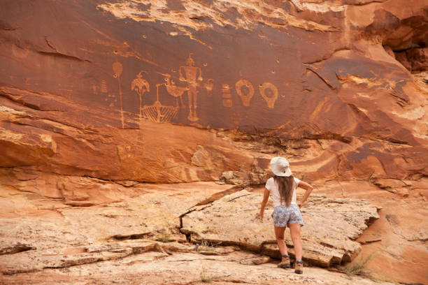 istock Young woman admires Comb Ridge Wolfman Panel Utah crane heron rock art 938754416