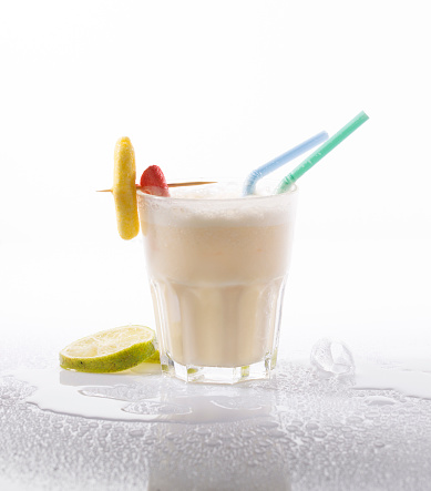 Batida served in a glass with straws on a background with drops of water