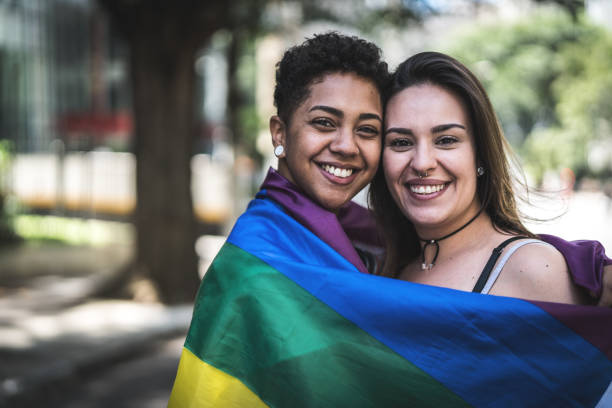 pareja de lesbianas con la bandera del arco iris - gay pride rainbow flag homosexual fotografías e imágenes de stock