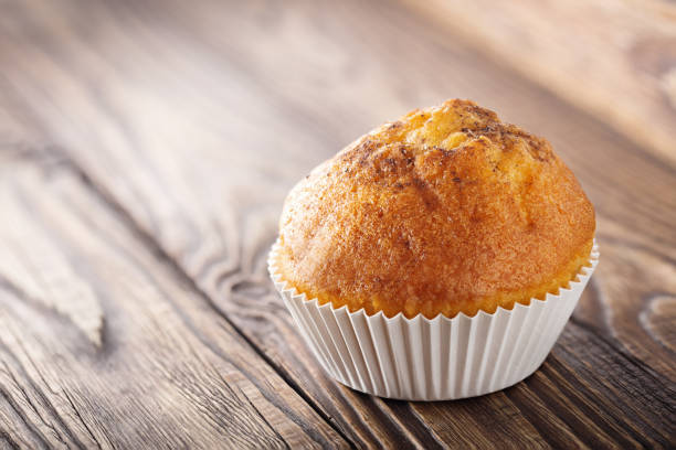 istock Classic muffins on a wooden old background in a white wrapper. 938760630