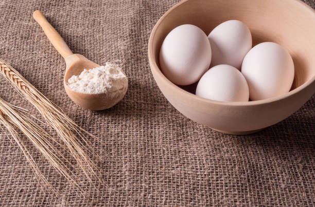 istock Spikes of wheat, spoon with flour and eggs on burlap 938764126