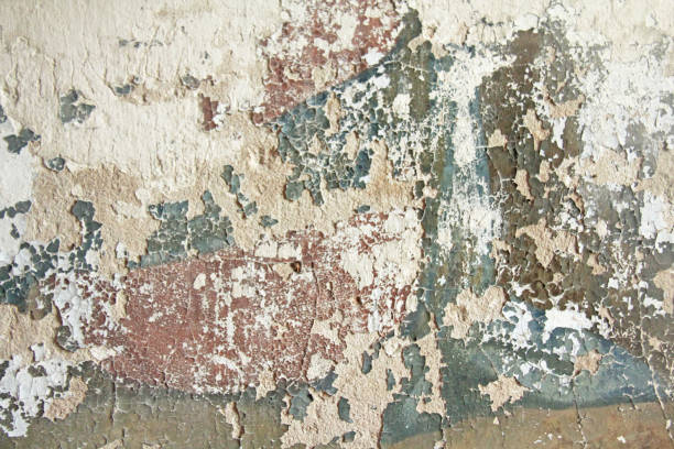 istock Old flaky white paint peeling off a grungy cracked wall. Cracks, scrapes, peeling old paint and plaster on background of old cement wall. An old cement stone wall as vintage cracked. Brick wall. 938770836