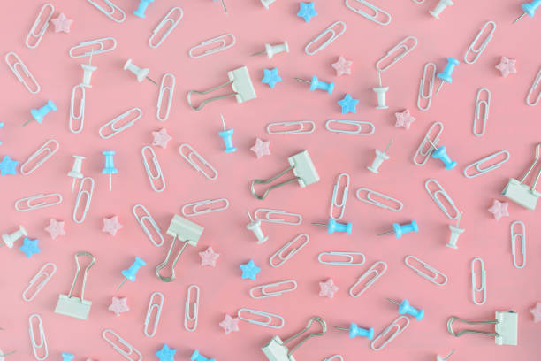 istock Bright pattern. Stationery chaotically scattered on a pink background. Staples, asterisks and buttons are in disarray. 938775588