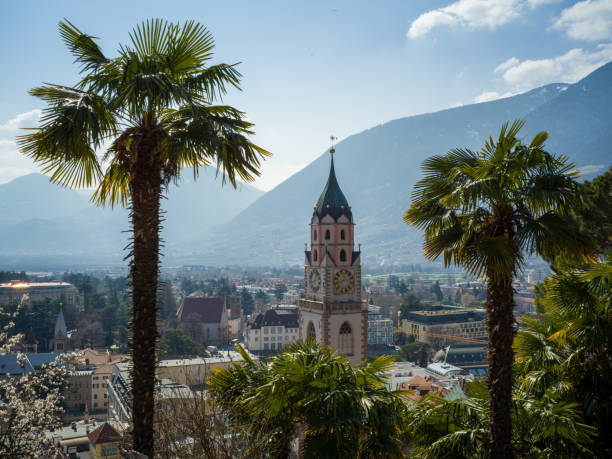 istock First trees blooming in Merano, Italy - Church tower and Mountains 938779218