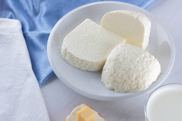 istock Cheese, dairy assortment on a white background, sandwich with soft cheese on a blue napkin, wooden background, wooden cutlery, white cheese on a white plate, kefir in a glass, art 938817302