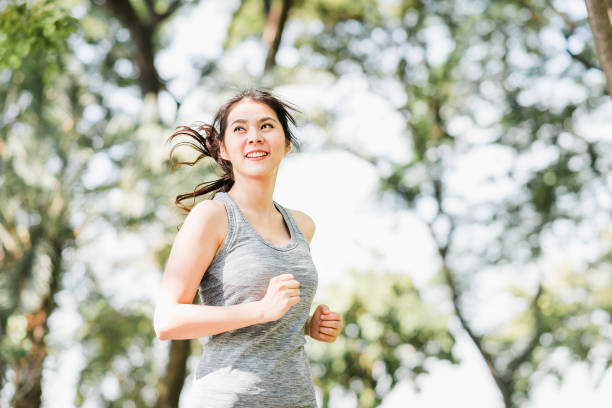 femme asiatique en bonne santé en cours d’exécution dans le parc - running jogging asian ethnicity women photos et images de collection