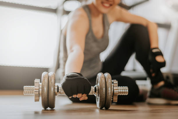istock woman picking up dumbbell on gym floor 938818082