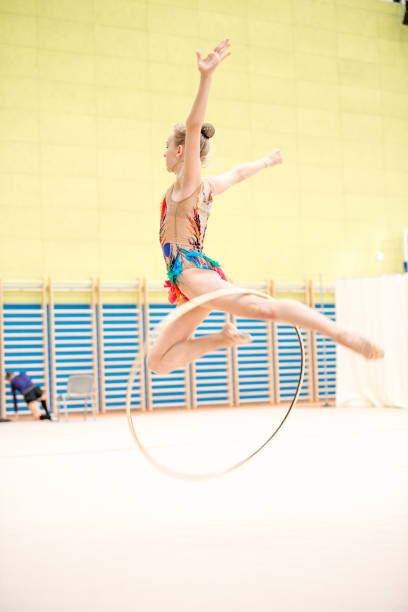 giovane atleta di ginnastica ritmica che cattura il cerchio a mezz'aria - skill side view jumping mid air foto e immagini stock