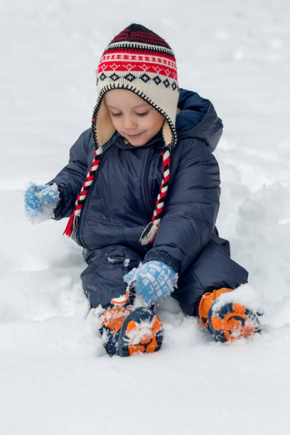 istock Little boy sitting in snow and playing 938820318