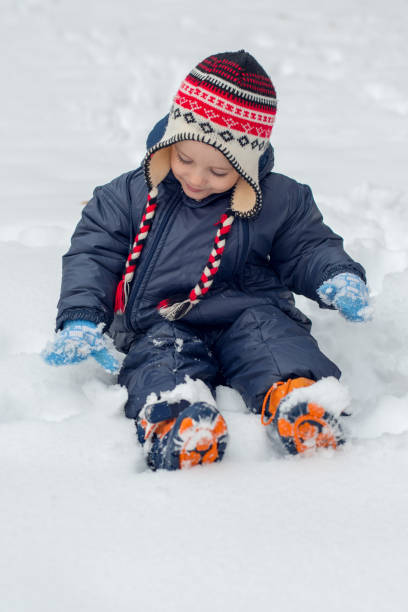 istock Little boy sitting in snow and playing 938820408