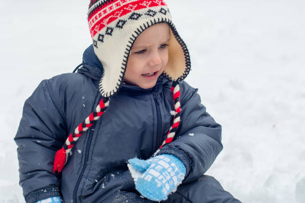 istock Little boy sitting in snow and playing 938831162