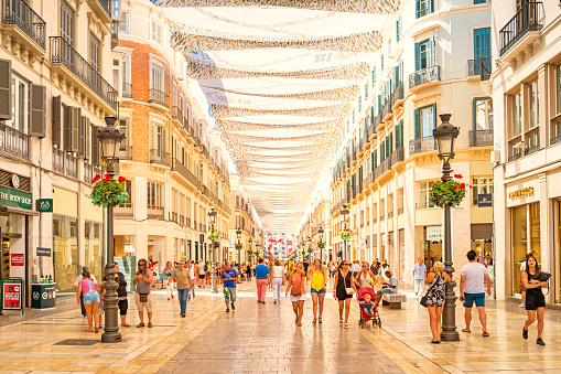 People walk on Calle Larios shopping street in downtown Malaga Spain on a sunny day.