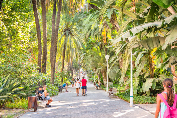 People walk in Parcue de Malaga, a lush downtown park, in Malaga Spain, on a summer day.