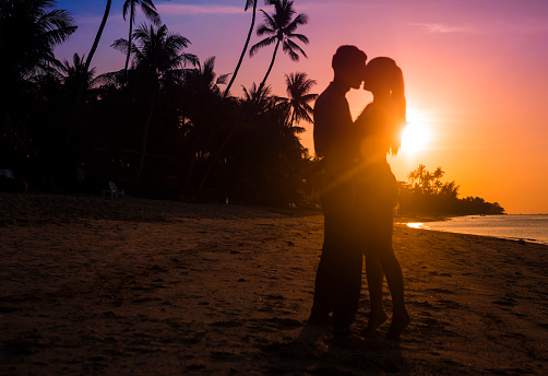 heterosexual couple hugging at sunset