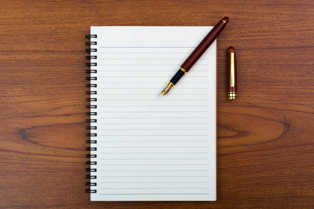 istock Fountain pen or ink pen with notebook paper on wooden working table with copy space, office desk concept. top view. 938849354