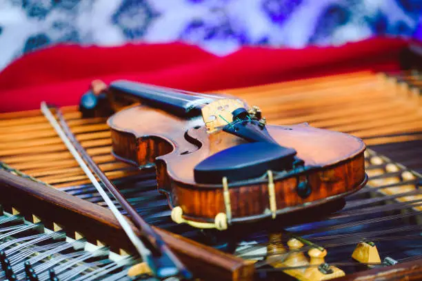 Violin in detail on cymbal. Dulcimer and violin with shallow depth of field and selective focus on the heart of the violin. Best picture of violin and cymbal.