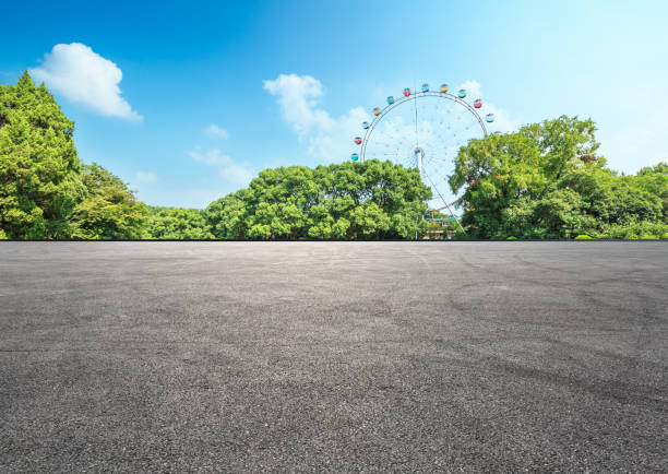 asphalt road and forest with playground ferris wheel