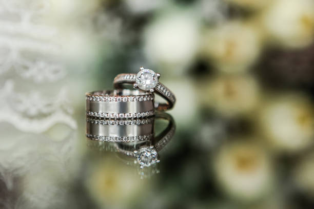 istock Wedding and engagement rings on the flowered glass background 938871136