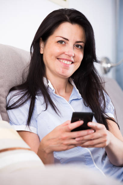 istock Smiling young female chatting in mobile phone 938876512