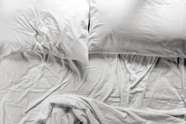 istock Unmade bed in a bedroom with two pillows and crumpled bed sheet 938880832