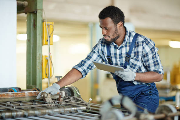 занят ремонт инженер с помощью планшета для анализа поломки - young men printing plant printing press factory стоковые фото и изображения