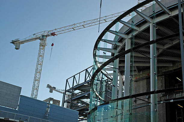 View of the construction site of a shopping center in Liverpool, UK. Several different modern building frames of different shapes (a round one in the foreground) and a construction crane in the background. Copy space, mainly blue and turquoise color.