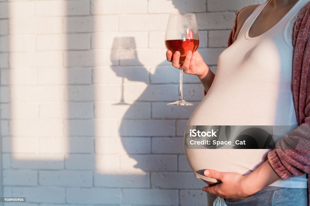 Pregnant woman with glass of red wine in hand Unrecognized Pregnant woman with glass of red wine in hand Pregnant Stock Photo