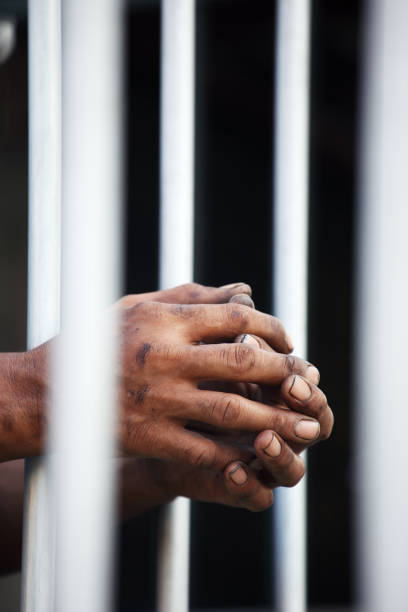 istock hand of prisoner in jail background. 938919170