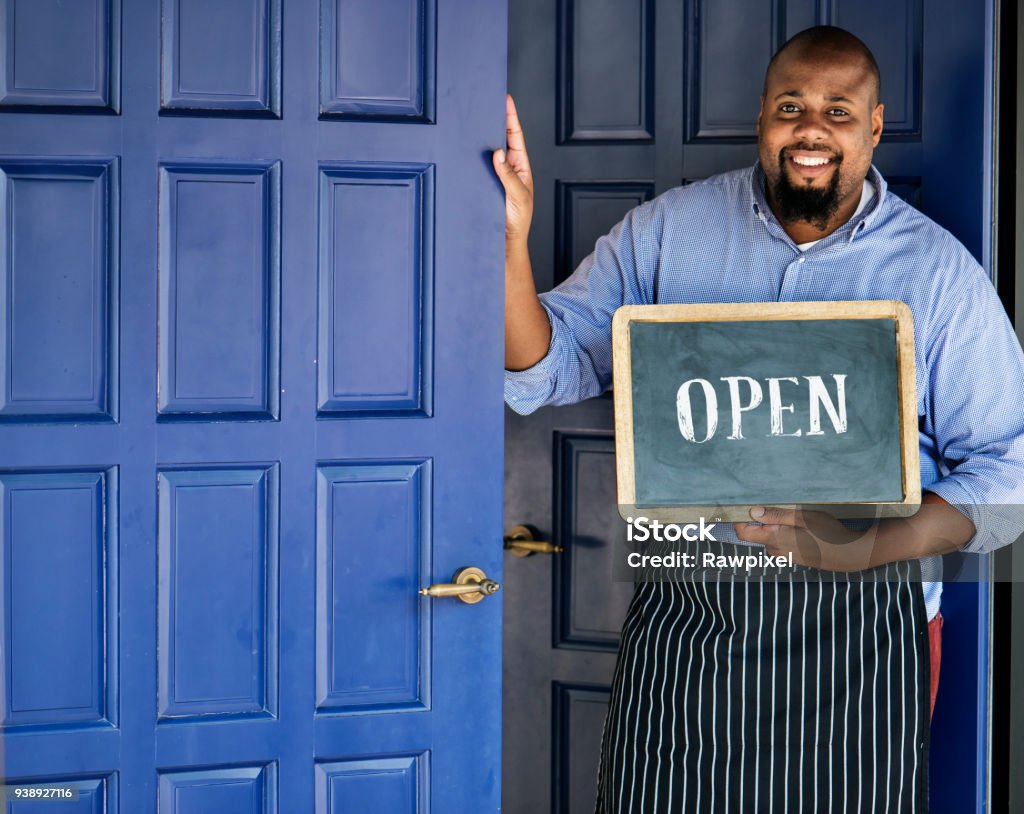 A cheerful small business owner with open sign Owner Stock Photo