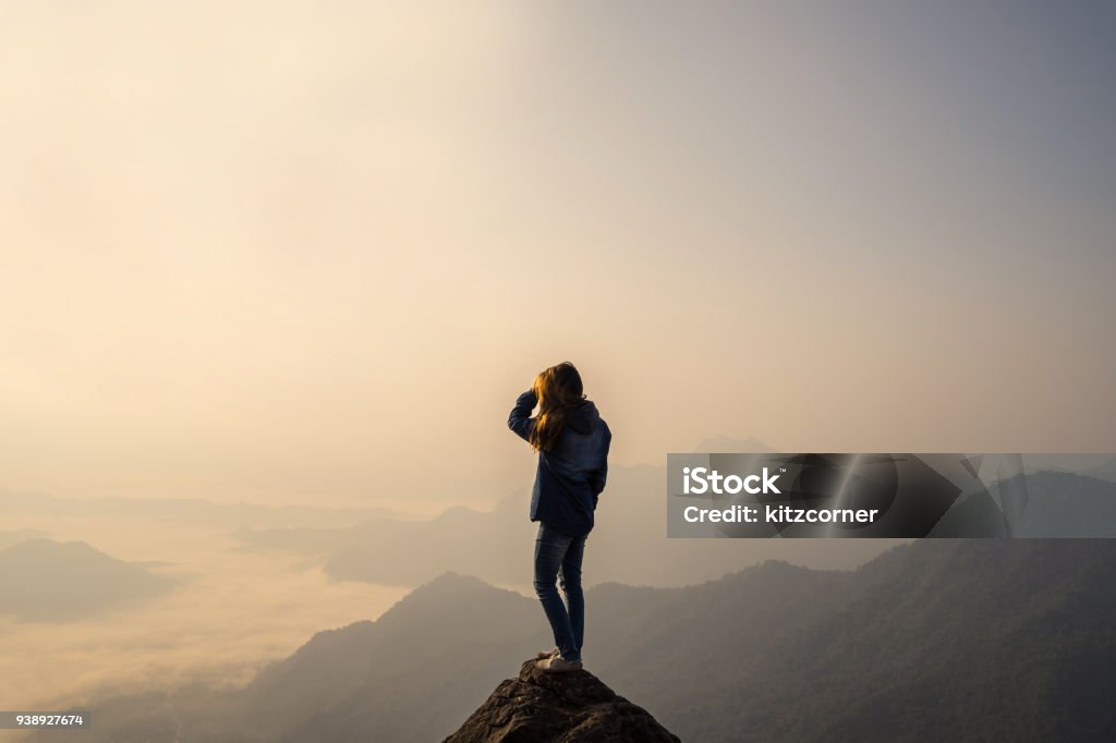 Young traveler standing and looking at beautiful landscape Young traveler standing and looking at beautiful landscape on top of mountain Cliff Stock Photo