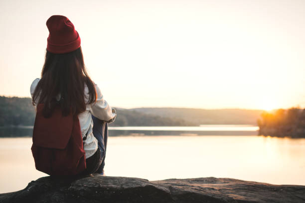 istock Woman With Backpack Sitting By Lake Against Clear Sky 938930634