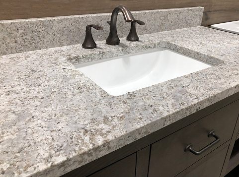 bathroom granite counter over wooden vanity cabinet and white rectangular sink with chrome faucet