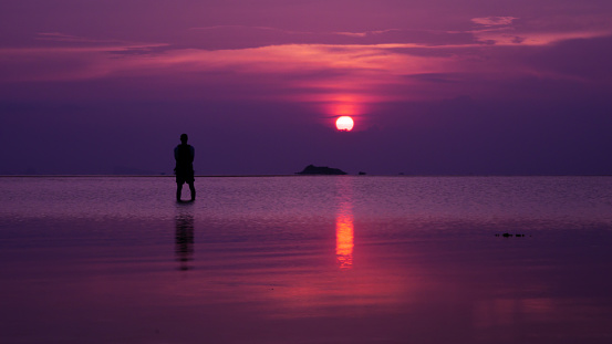 Follow your dreams, silhouette of man standing in sea at sunset
