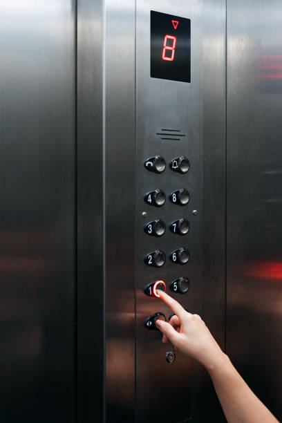 Female hand pressing elevator button going downward stock photo