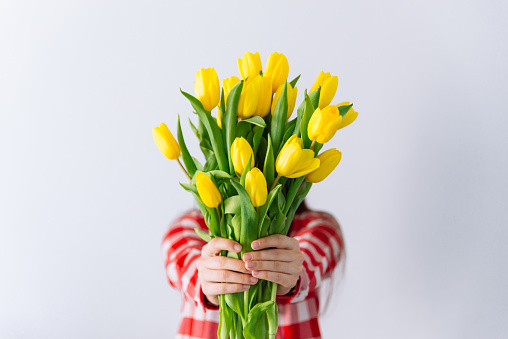 woman hold bouquet of yellow tulips. cover face with flowers. spring romantic concept