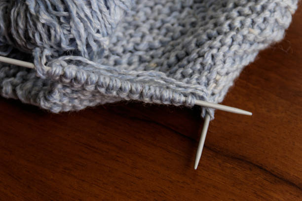 istock Process of knitting. Knitting wool and knitting needles on wooden table 938972810