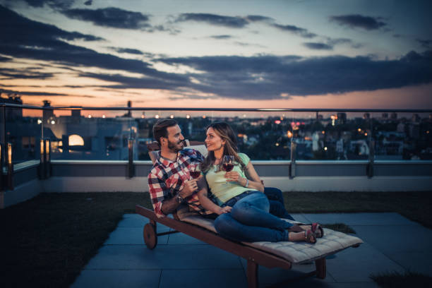 istock Happy couple communicating while enjoying in wine on a penthouse terrace at twilight. 938973598